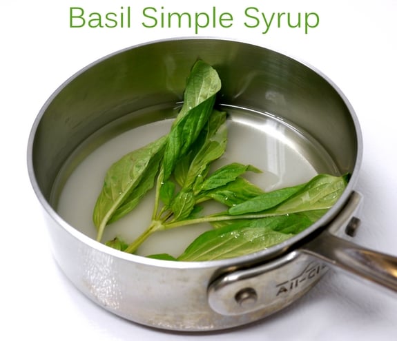 Basil Simple Syrup in text with basil leaves floating in a pan.