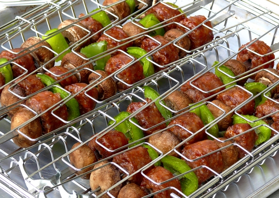 Two kabob grilling baskets filled with sausage kabobs.