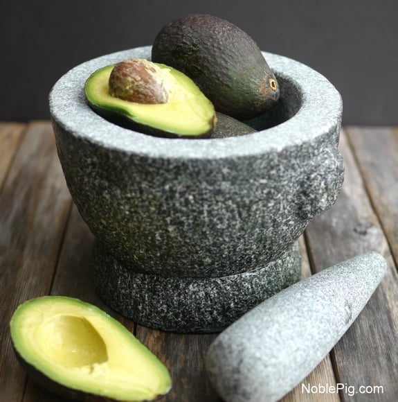 Halved avocados in a picture with a Mortar and pestle.