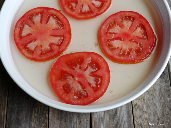 Sliced tomatoes sitting in a bowl with marinade.