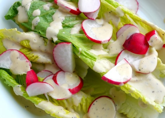 Creamy Parmesan Salad Dressing on the lettuce with radishes.