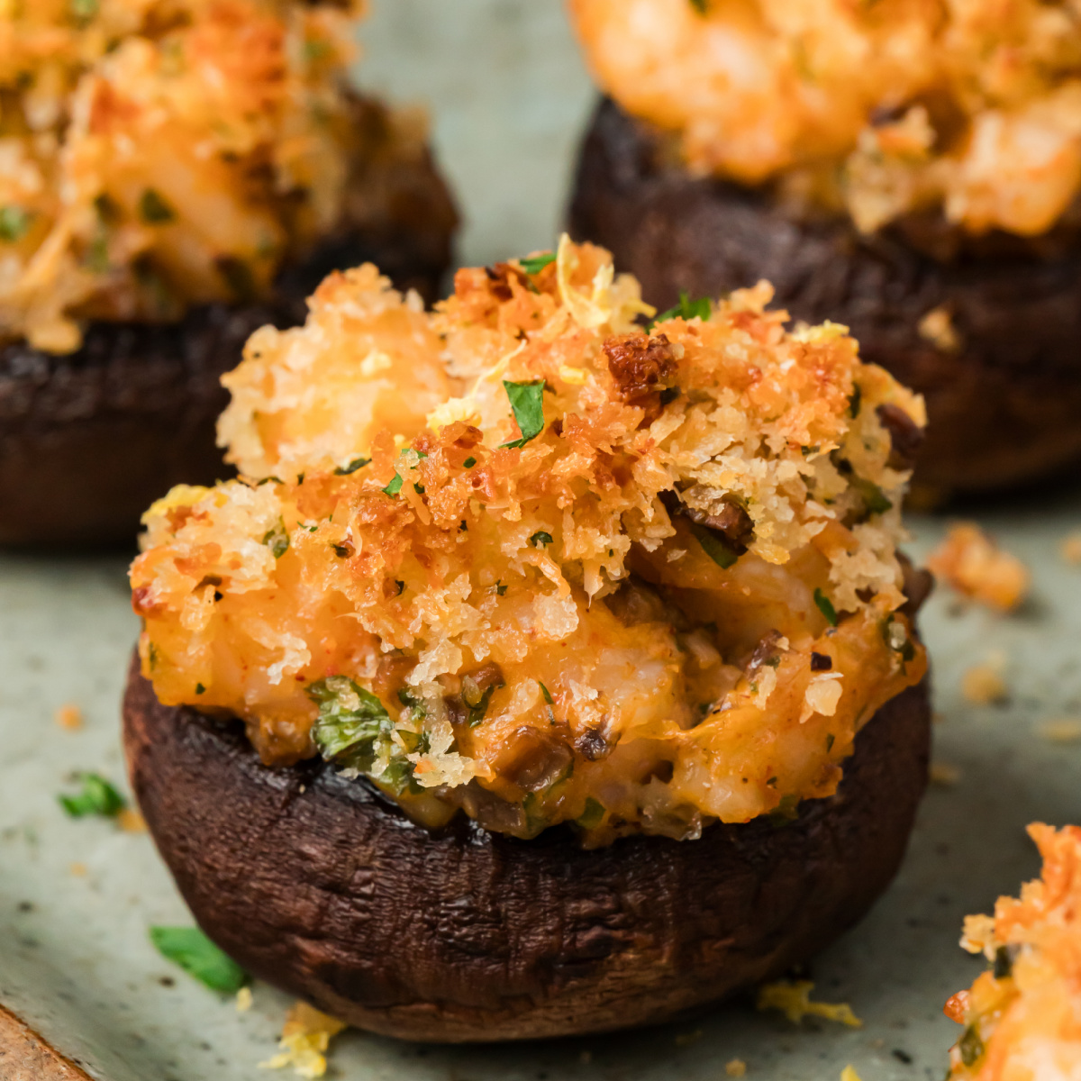 Close-up of a shrimp stuffed mushroom filled with chopped shrimp and topped with golden Parmesan panko and parsley