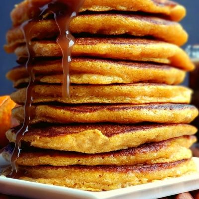 Stack of pancakes with syrup pouring.