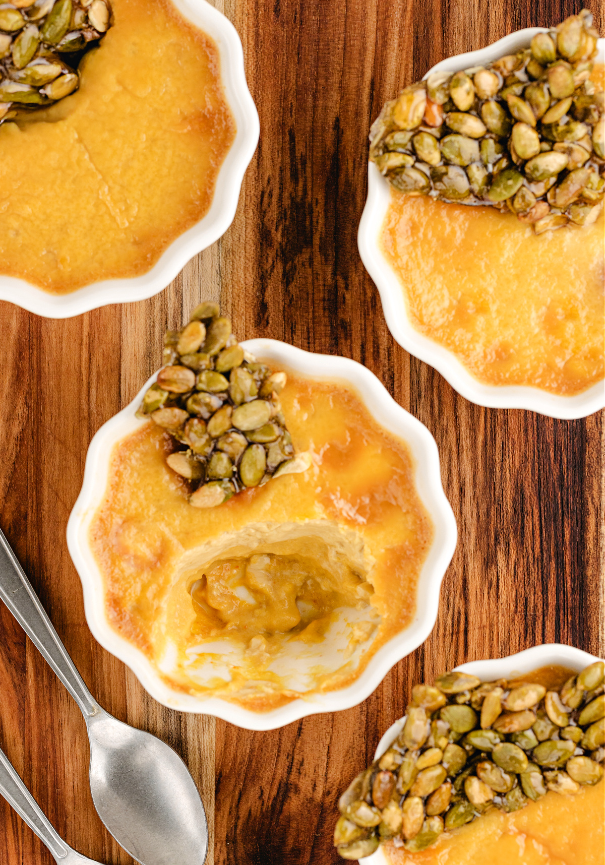 Pumpkin Chai Pots de Cr&egrave;me with a spoonful taken out to show the creamy chai-spiced pumpkin custard beneath the brittle topping.