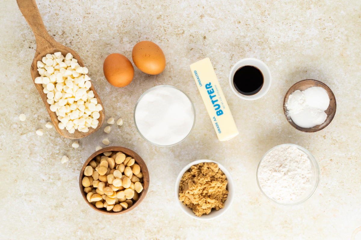ingredients for white chocolate macadamia nut cookies including butter sugar eggs flour white chocolate chips and macadamia nuts