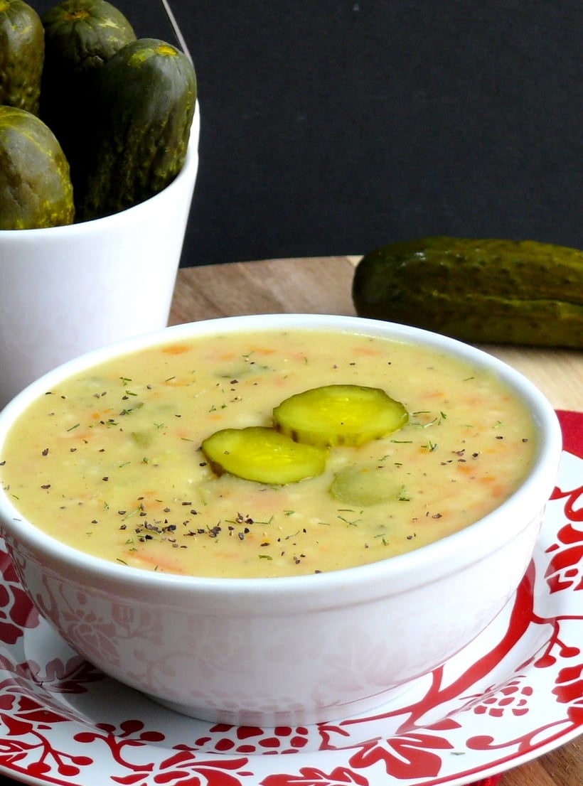 Bowl of dill pickle soup with pickles in the background.