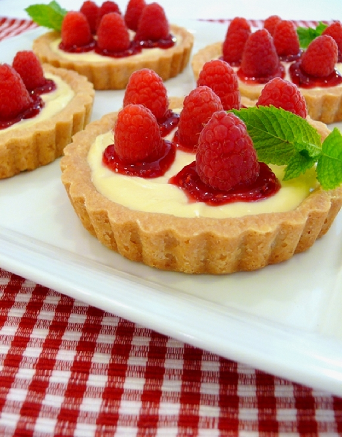 Raspberry Lemon Tartlets with a melted-butter shortbread crust, creamy lemon filling, raspberry jam, and fresh raspberries. Raspberry Lemon Tartlets topped with fresh raspberries and raspberry jam in buttery shortbread tart shells.