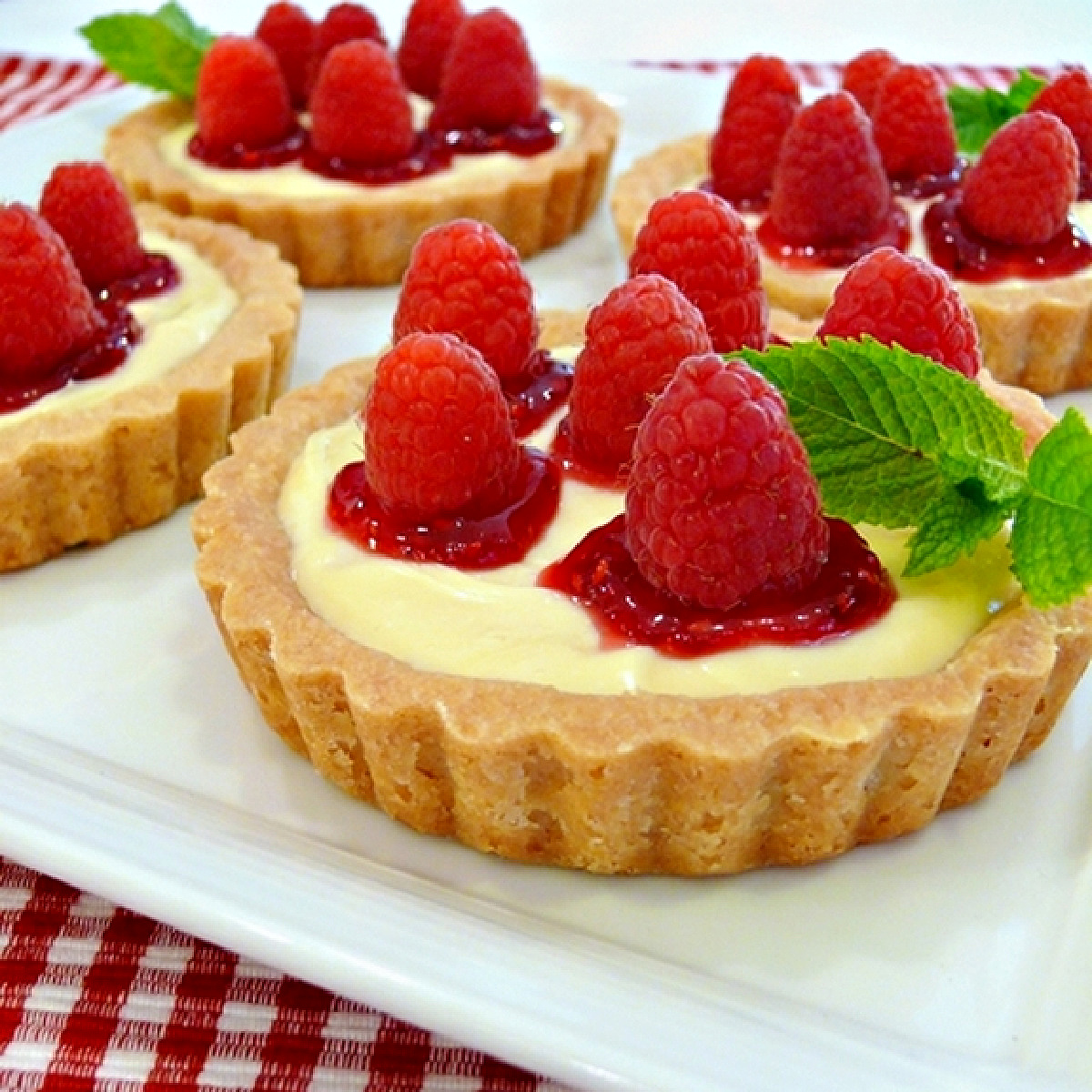 Raspberry lemon tartlets with shortbread crusts, lemon curd cream cheese filling, raspberry jam, and fresh raspberries.