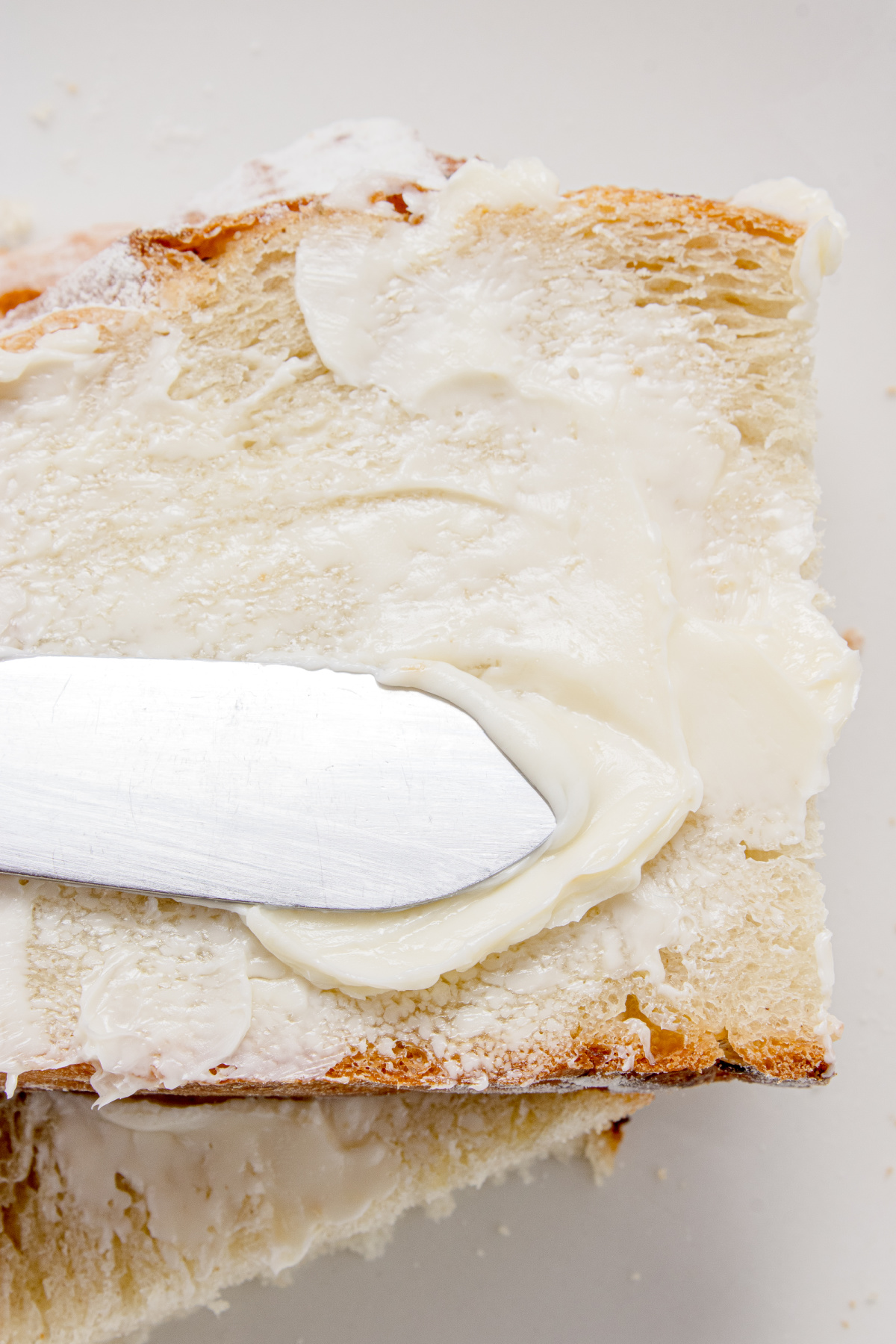 Buttered artisan rosemary bread slice Slice of artisan rosemary bread spread with soft butter showing the airy crumb and crisp crust