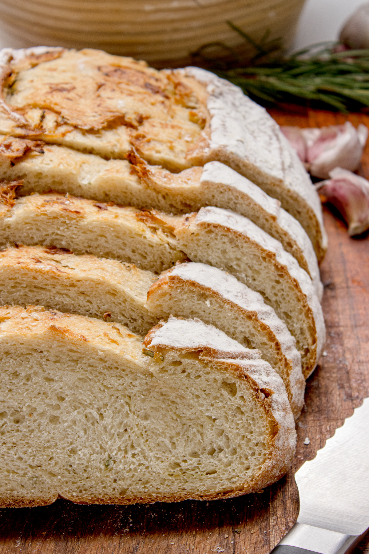 Soft crumb artisan rosemary bread slices Sliced artisan rosemary bread showing the soft chewy crumb and roasted garlic layered through the loaf