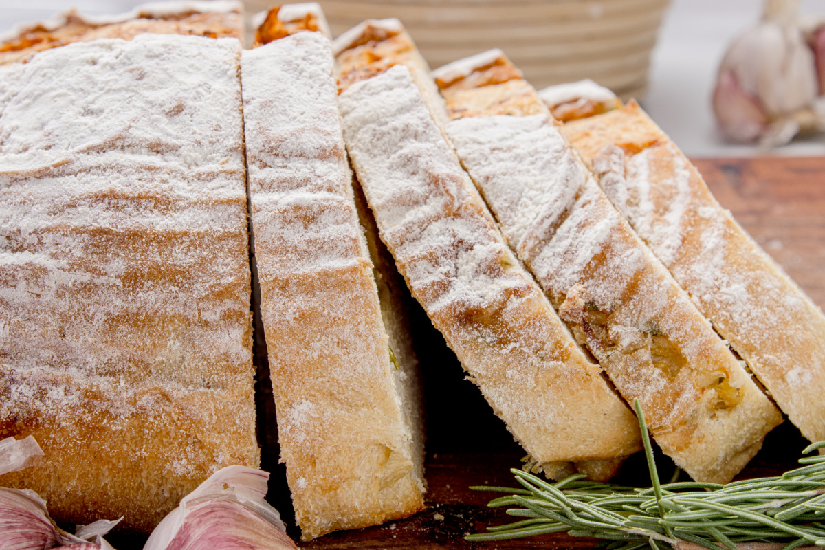 Slices of roasted garlic rosemary artisan bread Sliced roasted garlic rosemary artisan bread showing the soft airy crumb and roasted garlic layered throughout