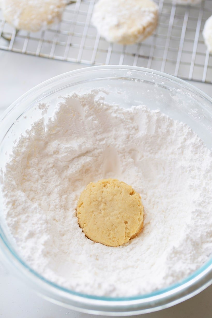 A bowl of powdered sugar with a panko cookie sitting in it ready to be coated.