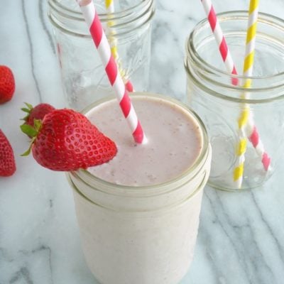 Strawberry Banana smoothie in a glass with empty glasses in the background.