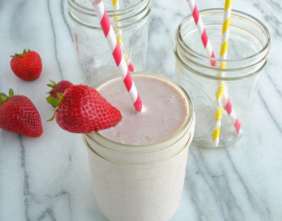 Protein Rich Strawberry Banana Cheesecake Smoothie in a glass with two empty glasses in the back, all with straws.
