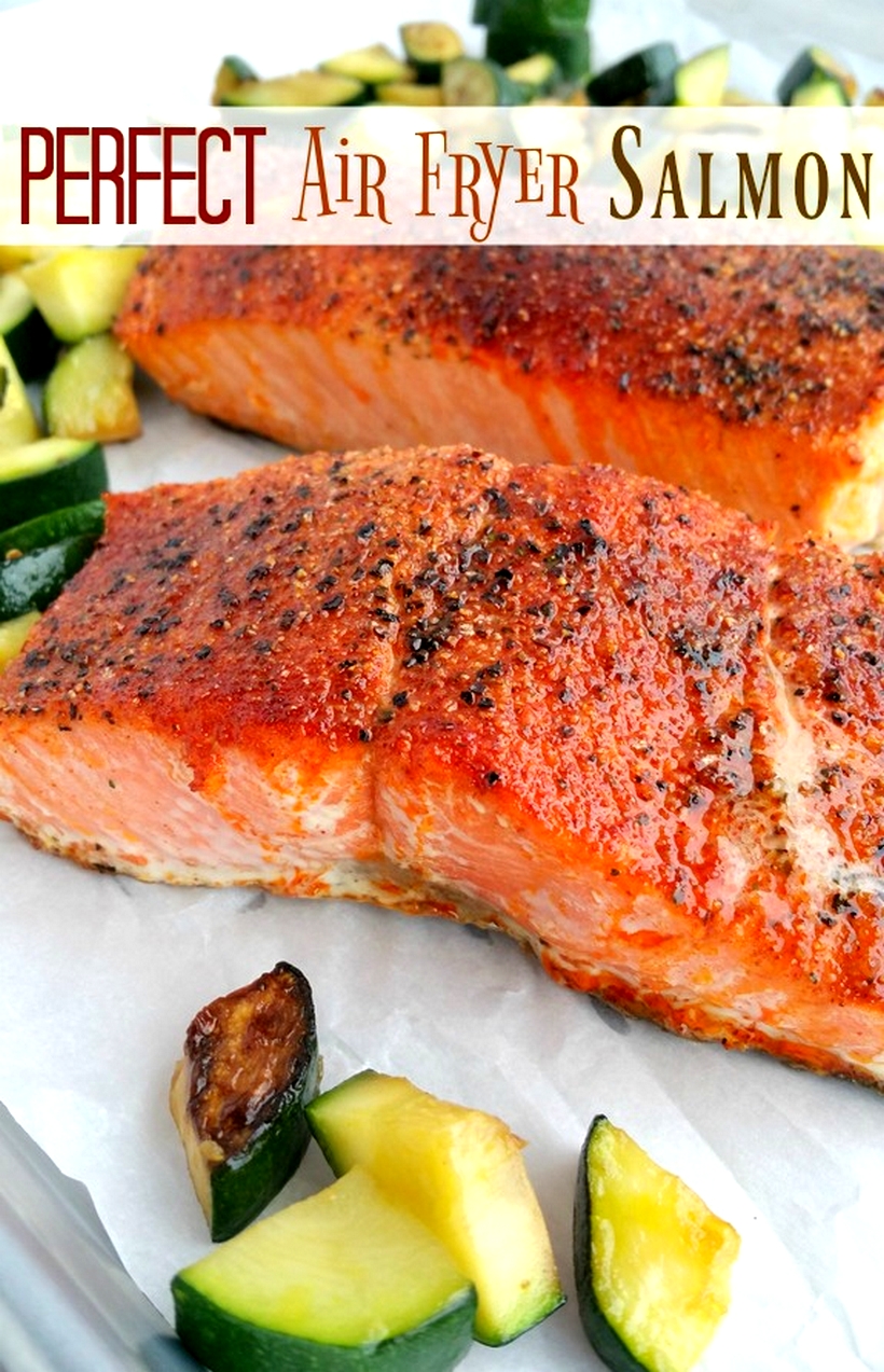 Two pieces of cooked salmon surrounded by veggies.