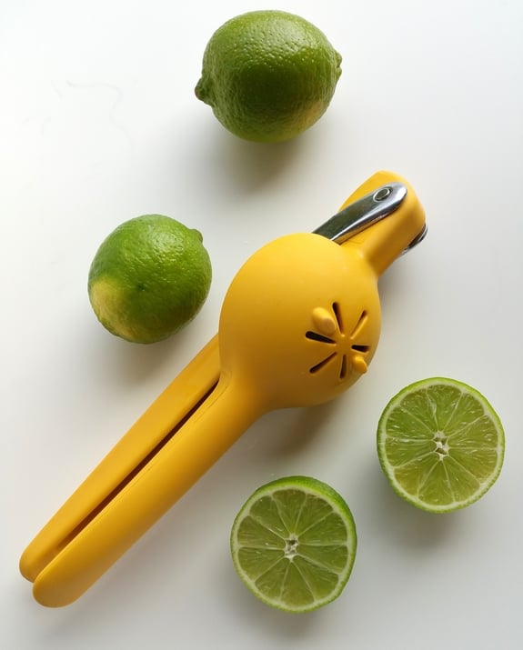 Citrus squeezer with whole and cut limes.