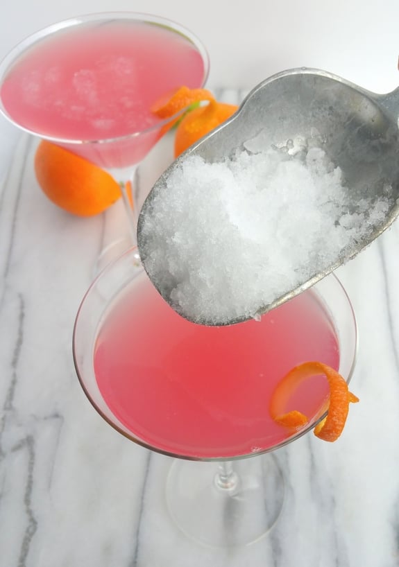 Two World's Best Cosmopolitan Cocktails with ice being scooped into them.