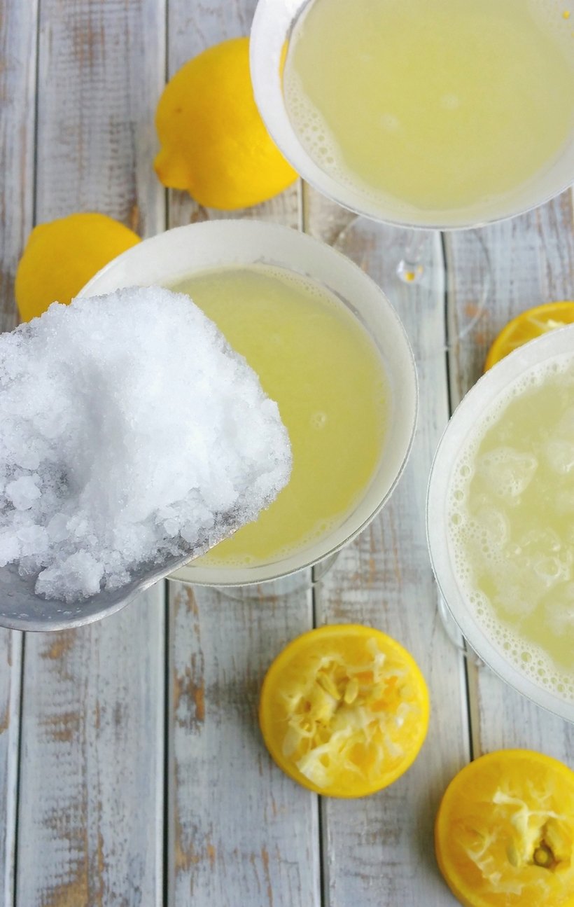 The perfect lemon drop martinis with ice being scooped into them.