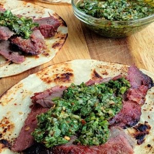 Flank steaks tacos, three of them, with bowl of chimichurri.