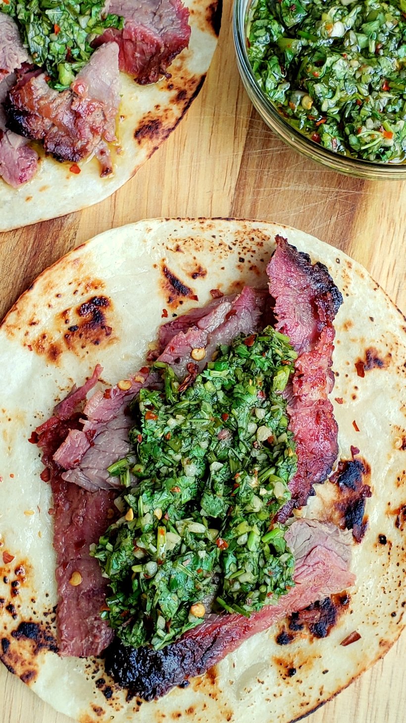 Overhead of Flank Steak Tacos with Garlicky Cilantro Chimichurri and a bowl of chimichurri.