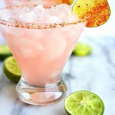 Icy Hibiscus Margarita surrounded by sqeezed limes