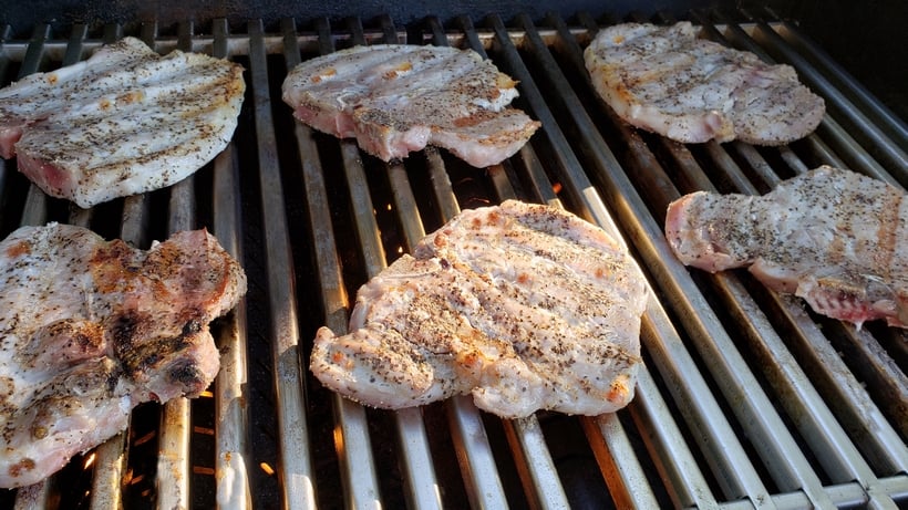 Pork chops cooking on a grill.