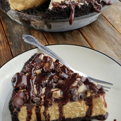 Slice of mud pie on a plate with whole mud pie in the background.