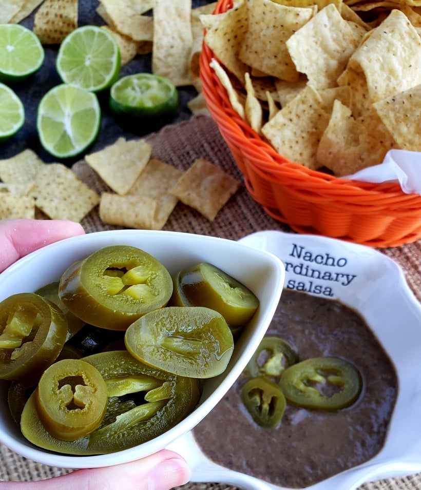 Salsa with a bowl of jalapenos and corn chips.