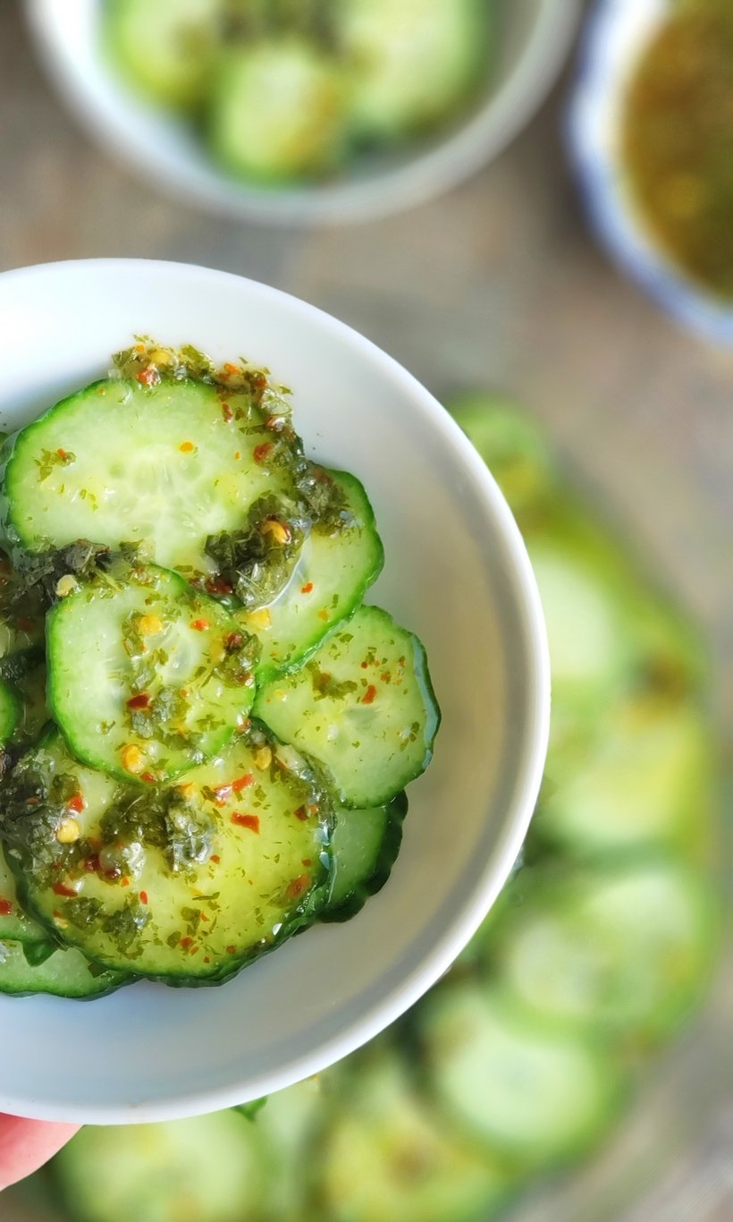 Sliced cucumbers in a bowl topped with vinaigrette.