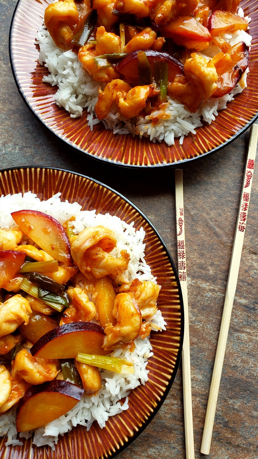 Easy Shrimp and Fresh Plum Stir-Fry over rice with chopsticks on two different plates.
