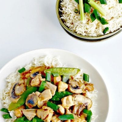 Chicken and snow pea stir-fry on a white plate.