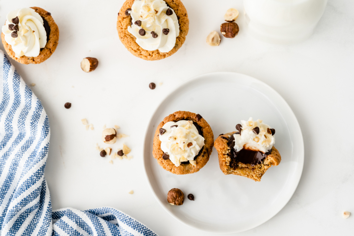 Nutella chocolate cookie cups topped with whipped cream and chocolate chips on a white plate