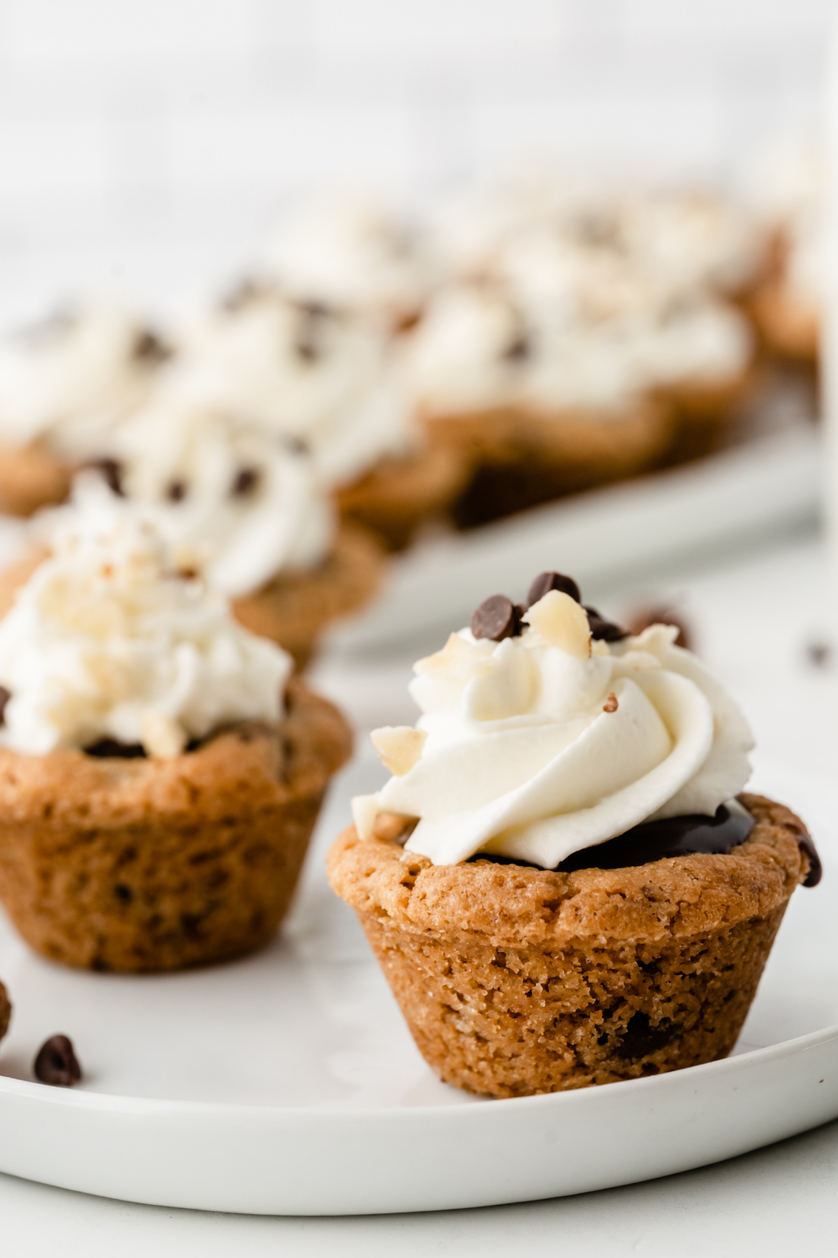 Nutella chocolate cookie cups topped with whipped cream and chocolate chips on a serving platter