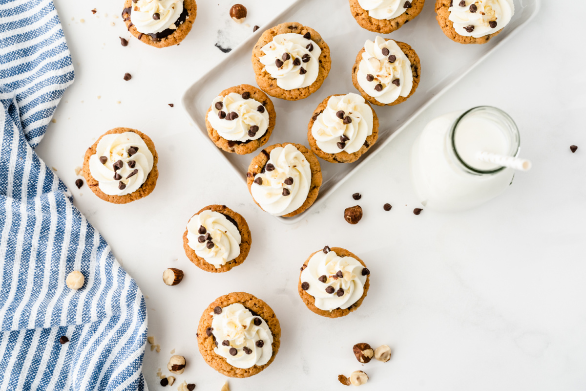 Nutella chocolate cookie cups arranged on a tray with whipped cream and chocolate chips