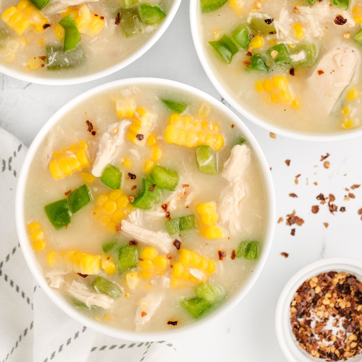 Overhead view of chicken corn chowder with fresh sweet corn, shredded chicken, and green bell peppers.