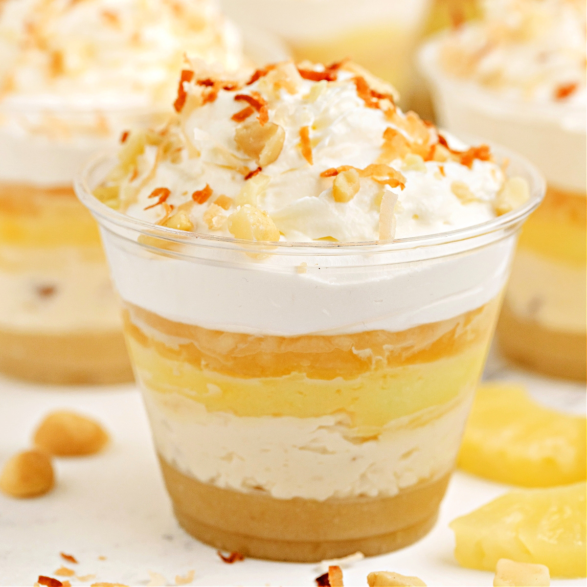 Square image of Hawaiian Dream Dessert Cup layered with macadamia crust, coconut pudding, pineapple, and whipped cream.