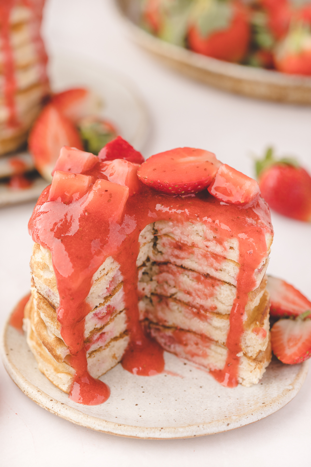 Fresh strawberry pancakes stacked high with warm strawberry sauce dripping over the sides and jammy strawberries cooked into the buttermilk batter.