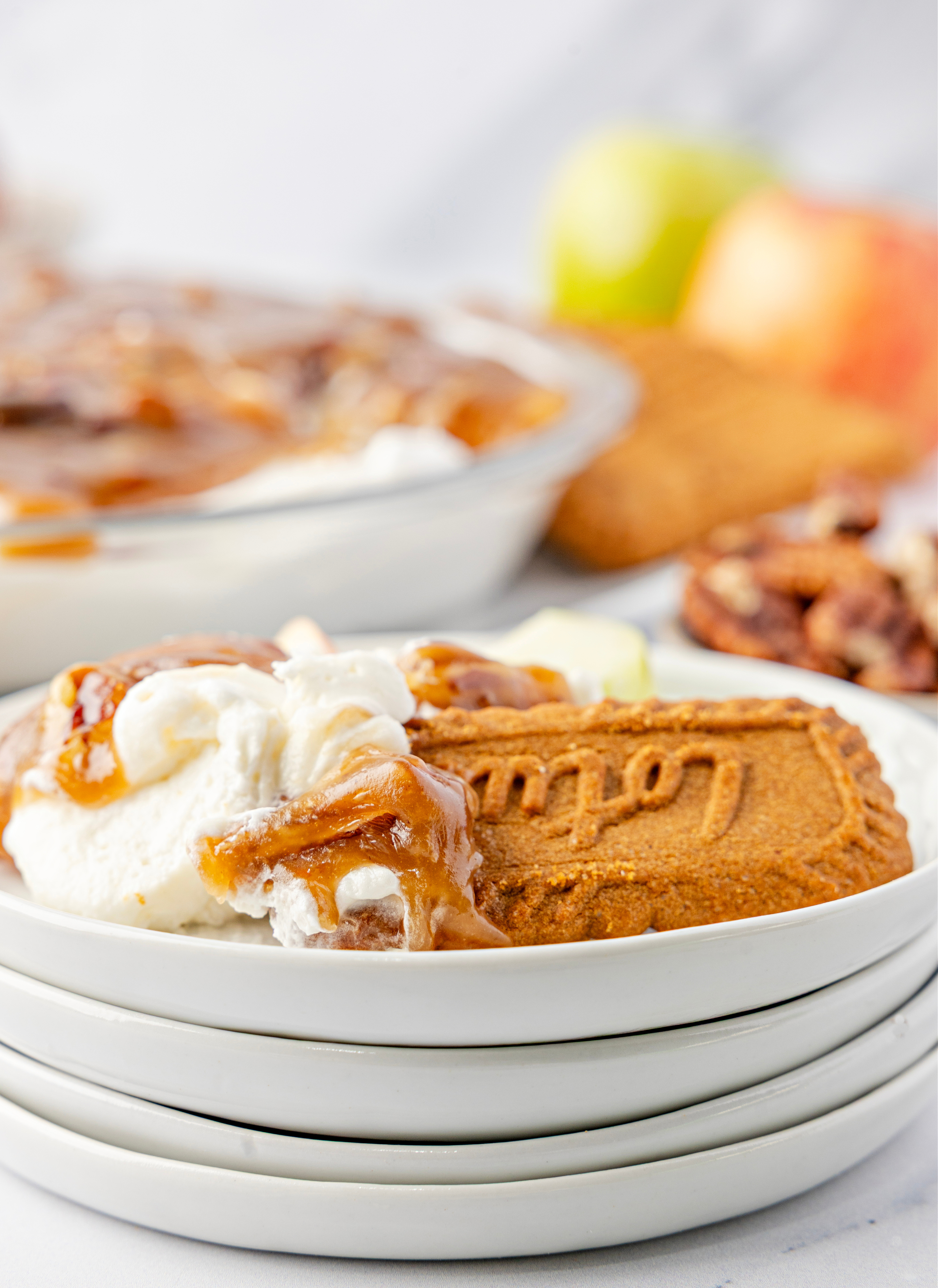 Serving of cream cheese dessert dip topped with warm caramel pecans on a small plate with a Biscoff cookie, showing the soft, scoopable texture.