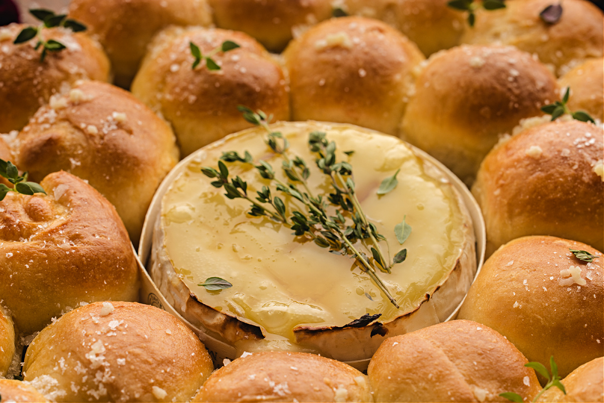 A close look at the melted Camembert in the center of the bread wreath, glossy and warm with fresh thyme.