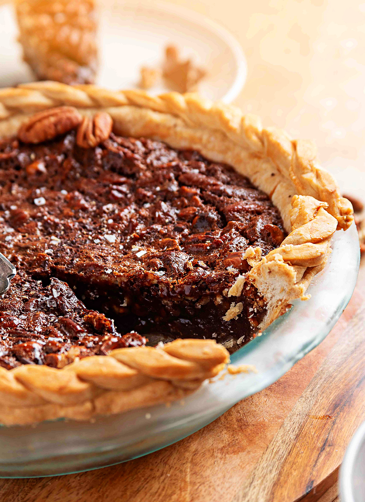 A partially sliced chocolate hazelnut pecan pie with a molten center and a thick braided crust along the rim.