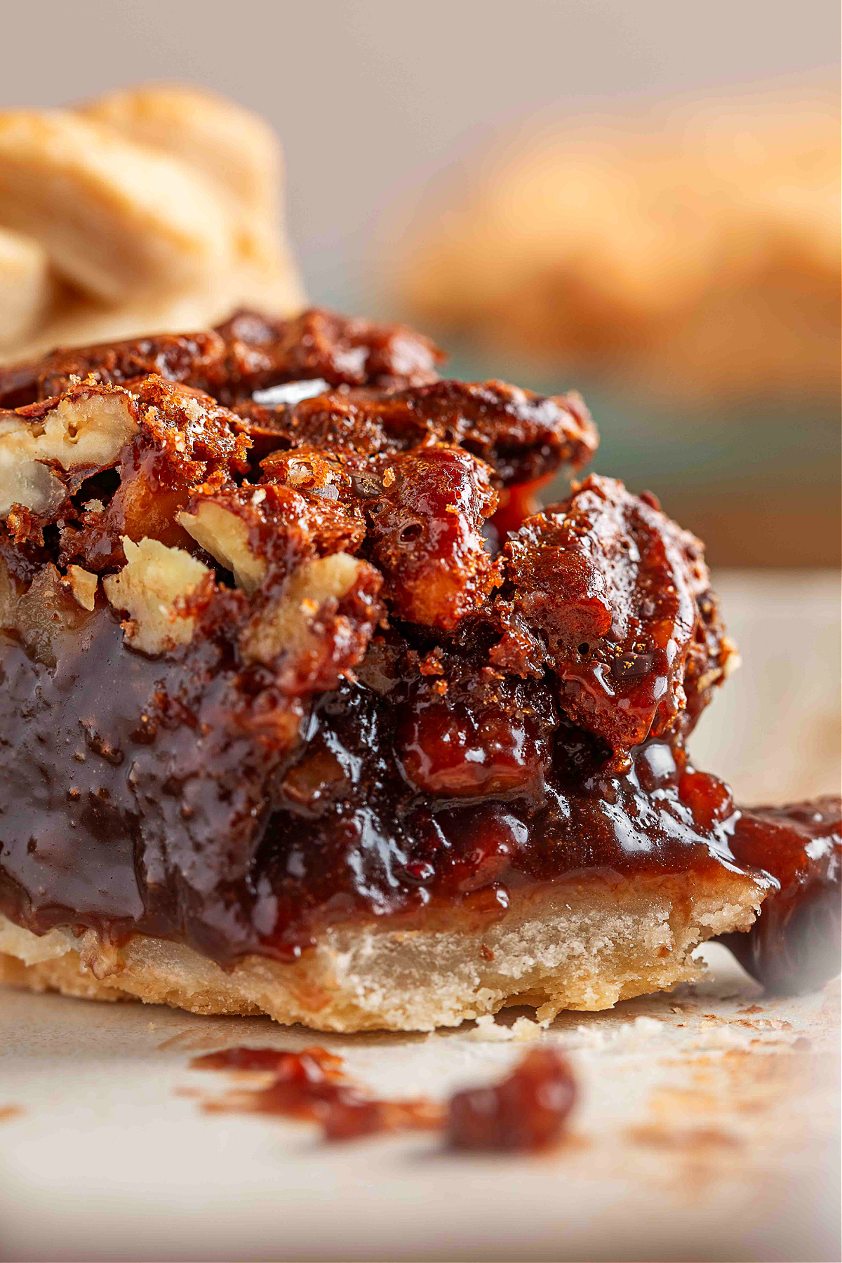 Close-up of a gooey slice of chocolate hazelnut pecan pie showing the molten Nutella custard and toasted nuts on a flaky crust.