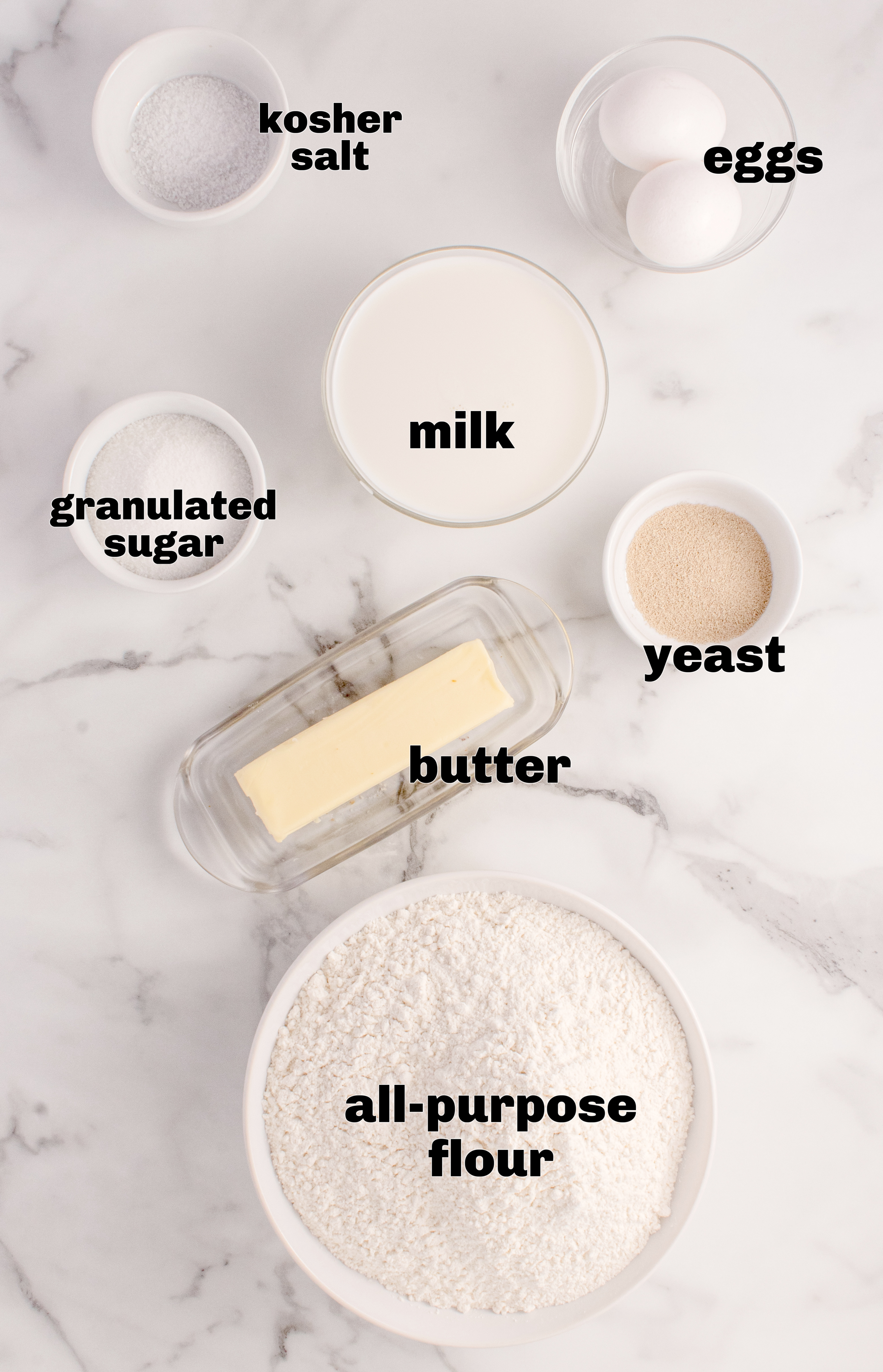 Ingredients for classic Parker House Rolls including flour, yeast, warm milk, butter, sugar, and eggs.