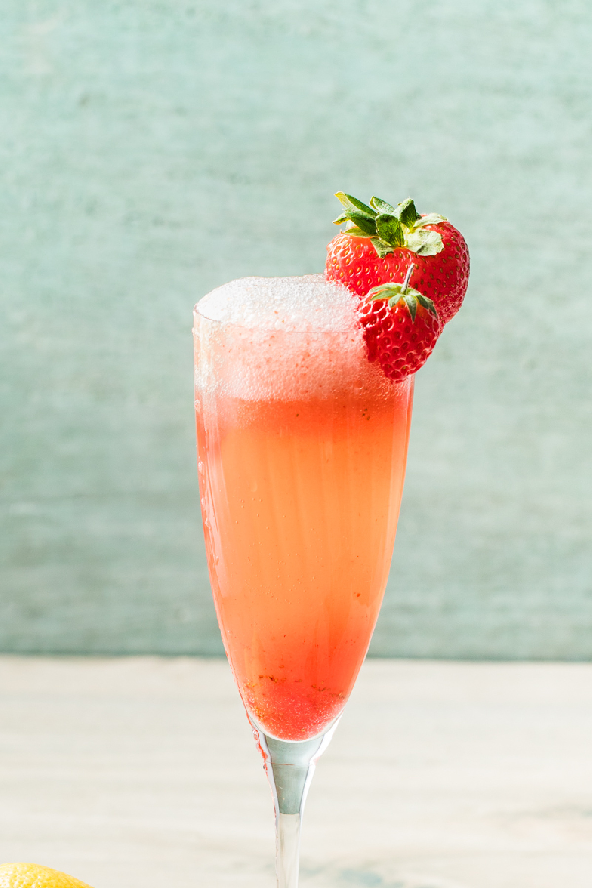 Strawberry bellini topped with fresh strawberry garnish and a light foam at the rim.