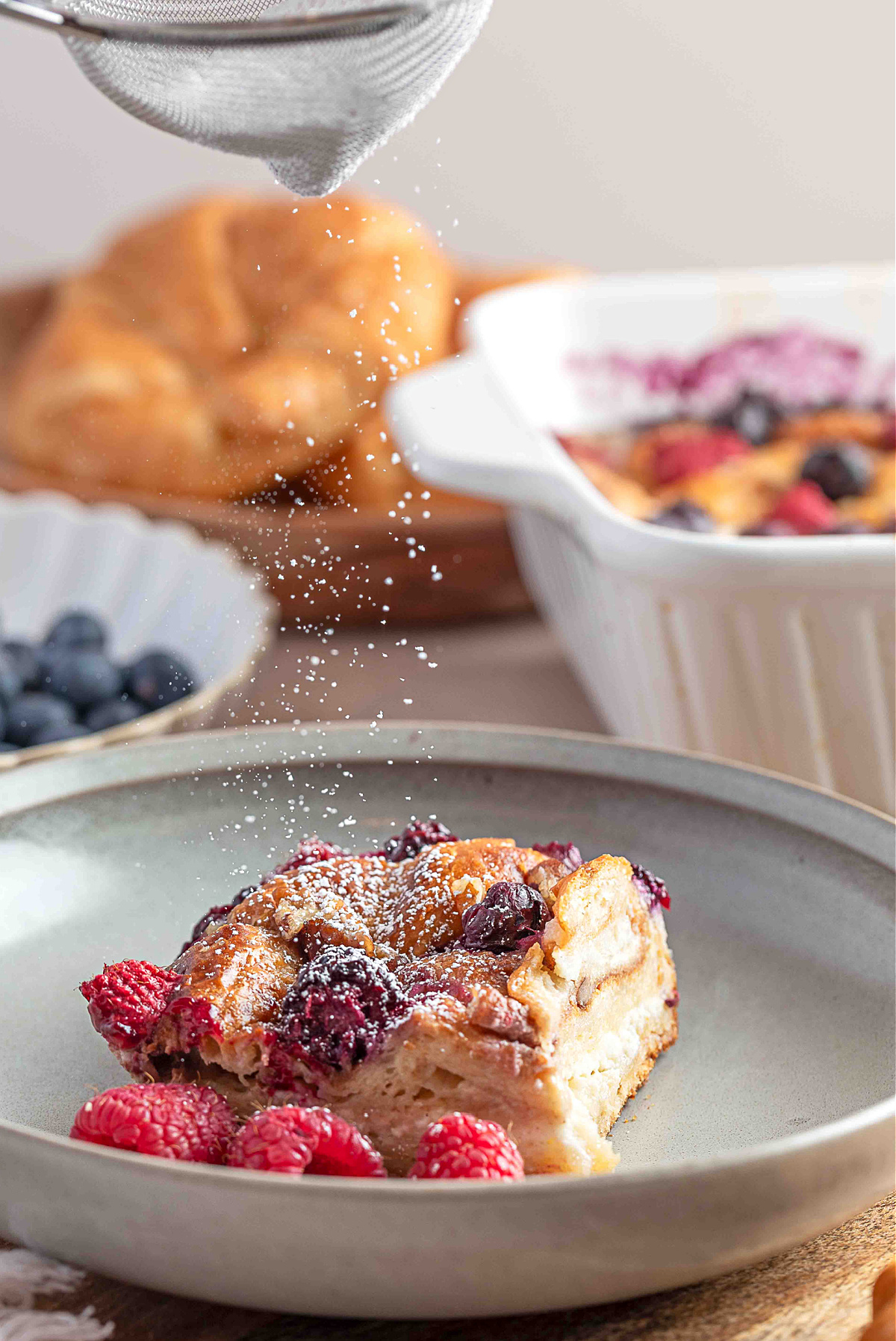 A close-up of the croissant French toast casserole showing a custardy interior layered with cream cheese and baked mixed berries.