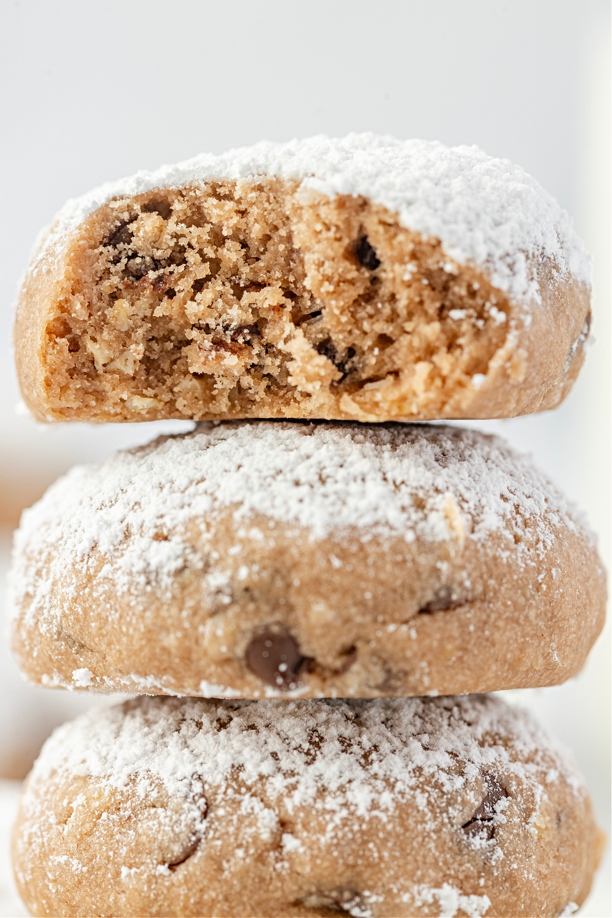 A bitten Danish wedding cookie stacked over two others, showing the soft interior and chocolate chip texture.
