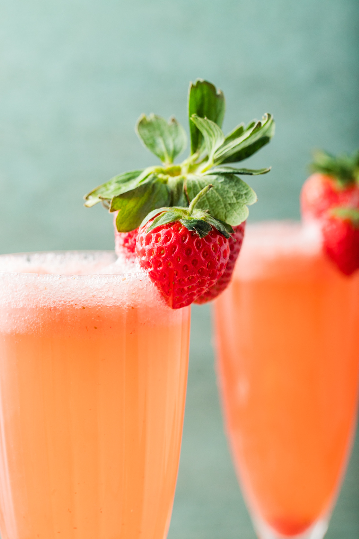 Bellini in a tall champagne flute with fresh strawberries clipped to the rim.