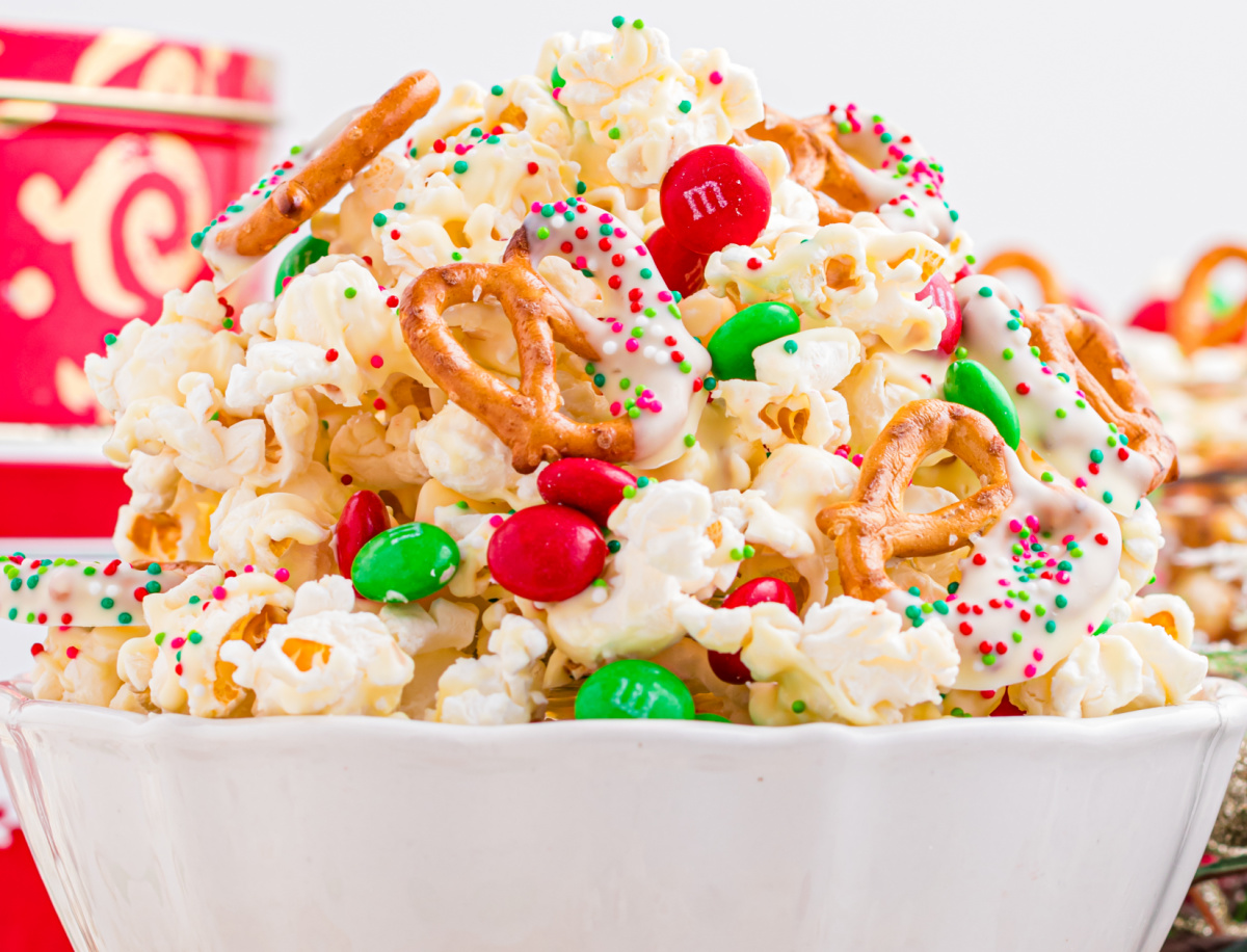 christmas popcorn mix in a white bowl revealing M&m's