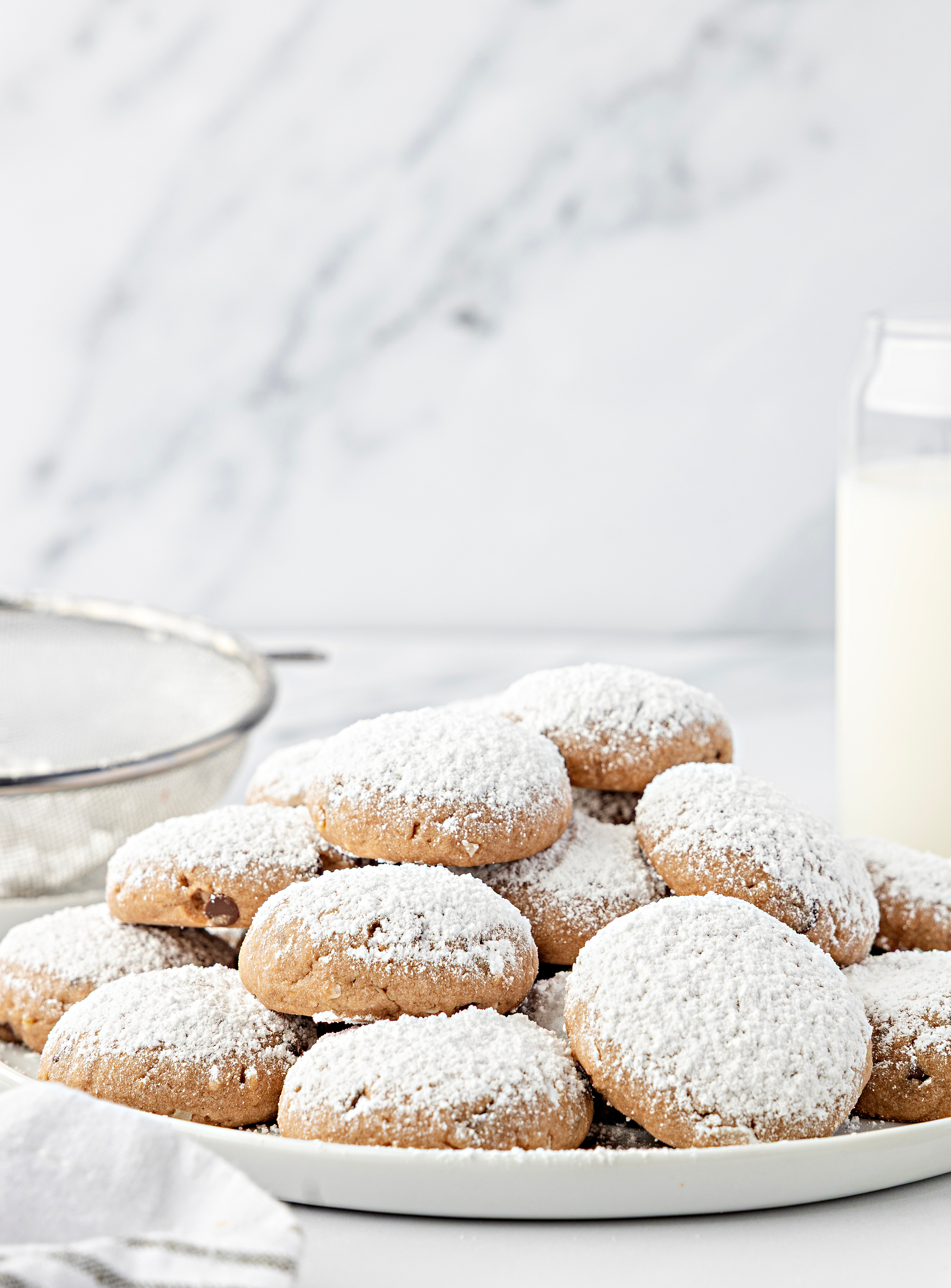 An overhead view of soft Danish meltaway cookies on a plate with a thick layer of confectioners&rsquo; sugar.