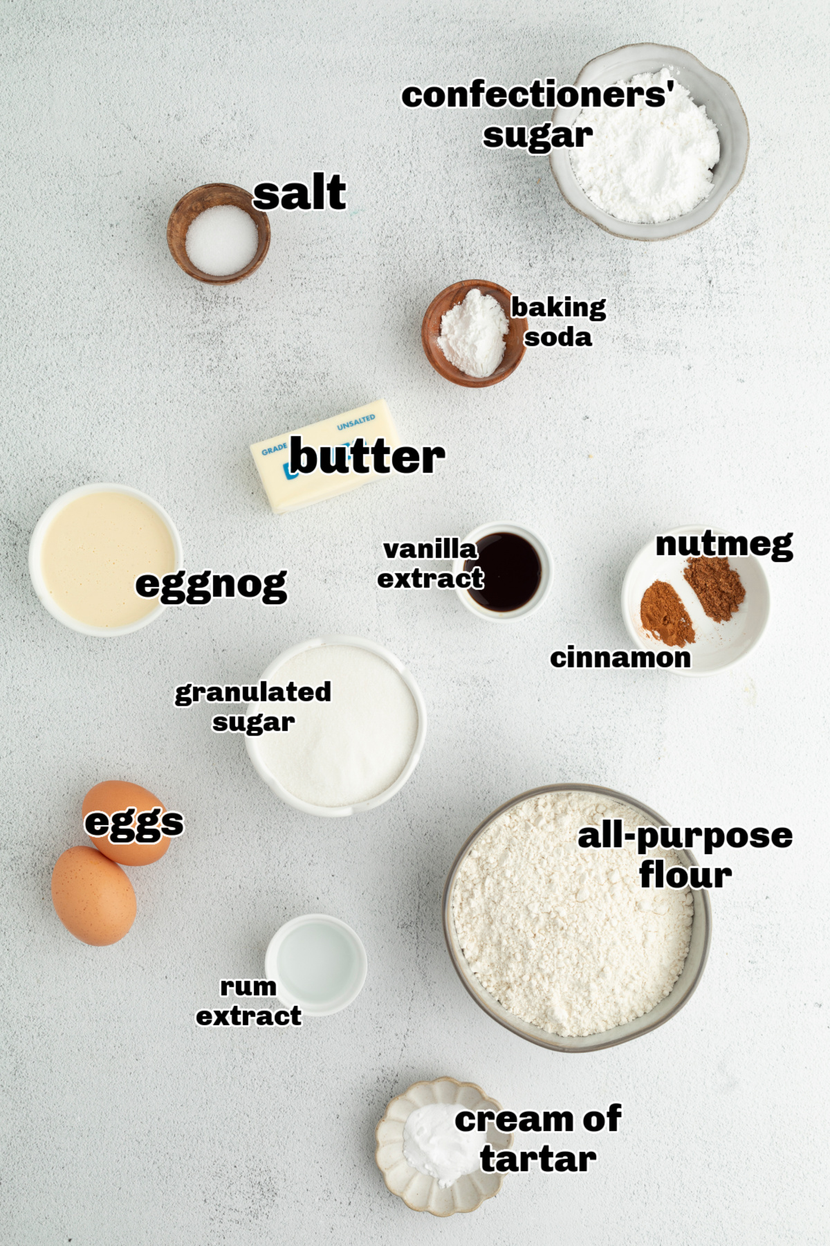 Measured ingredients for eggnog snickerdoodles arranged on a light surface, including eggnog, flour, spices, and butter.