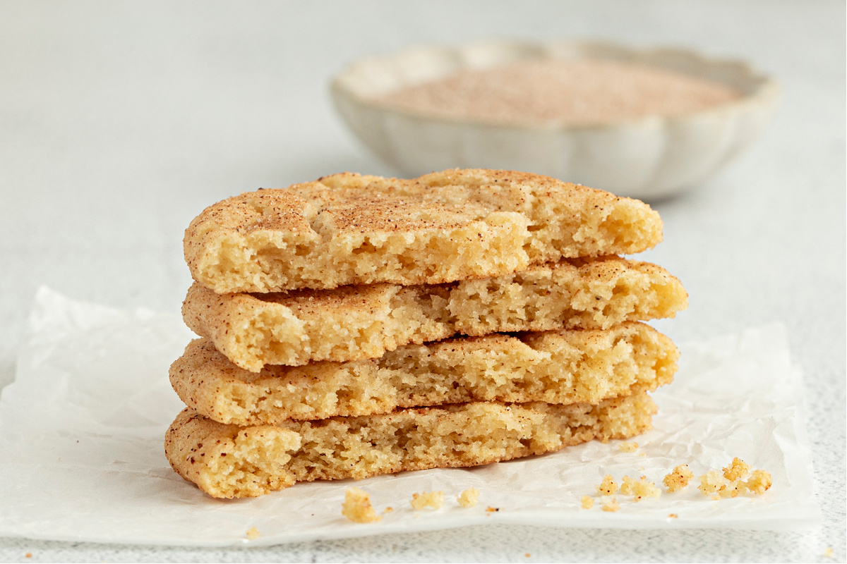 Overhead view of eggnog snickerdoodles cooling on parchment paper, highlighting their soft, tender texture.